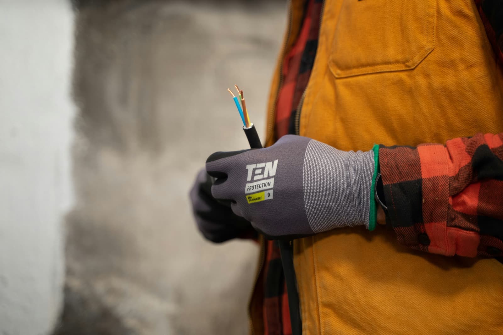 Electrician's gloved hand wiring a junction box